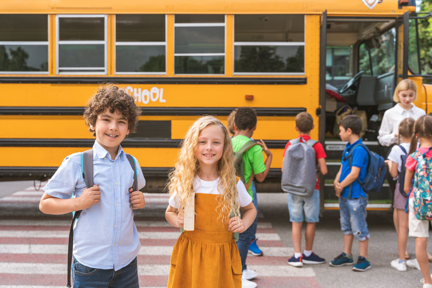 Group of young students attending primary school on a yellow school bus