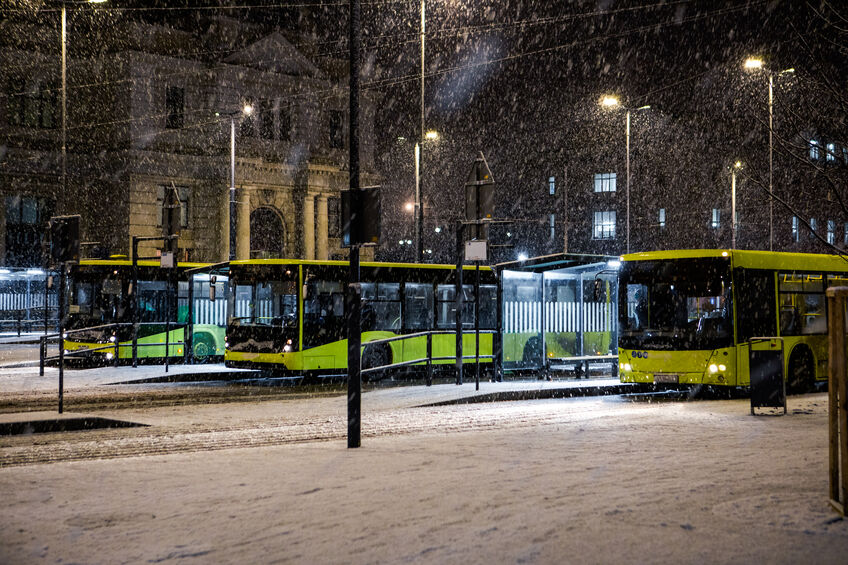 Three buses at bus stop in front of reconstructed lviv railway station snowing winter night