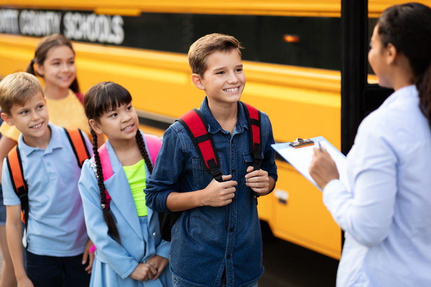 Happy school children waiting to get on school bus