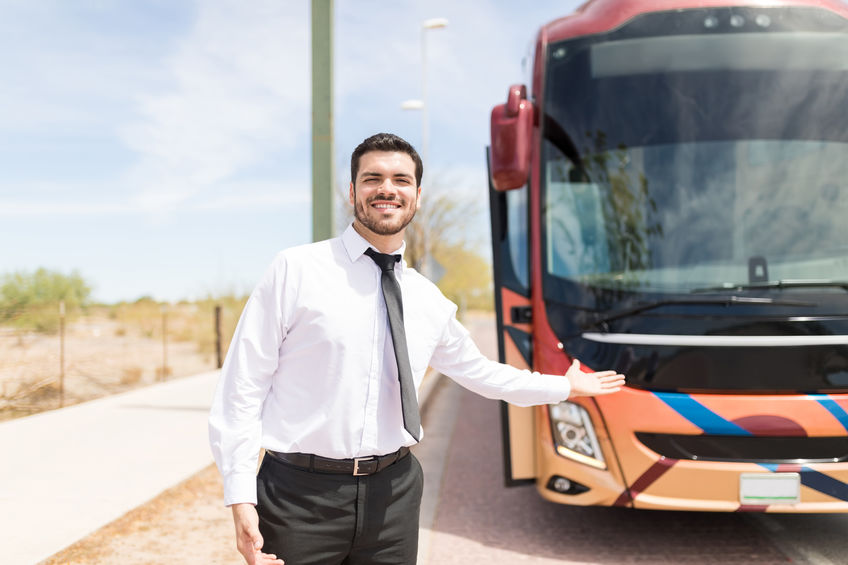 young man coach bus driver making eye contact while inviting into the travel bus